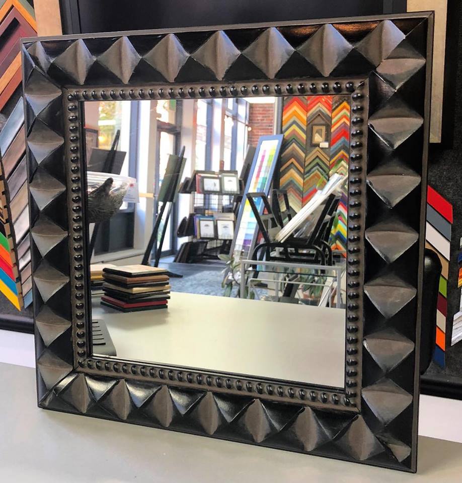 Custom framed mirror featuring a black geometric designer frame with pyramid detailing and decorative beaded inner edge